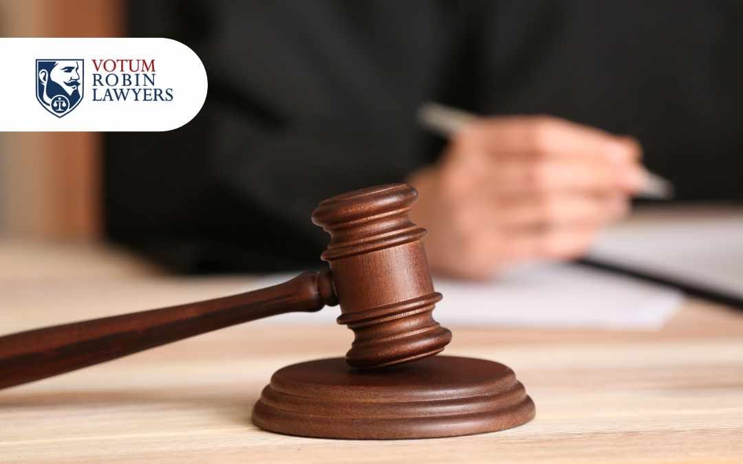 młotek sędziowski, w tle prawnik podpisuje dokumenty