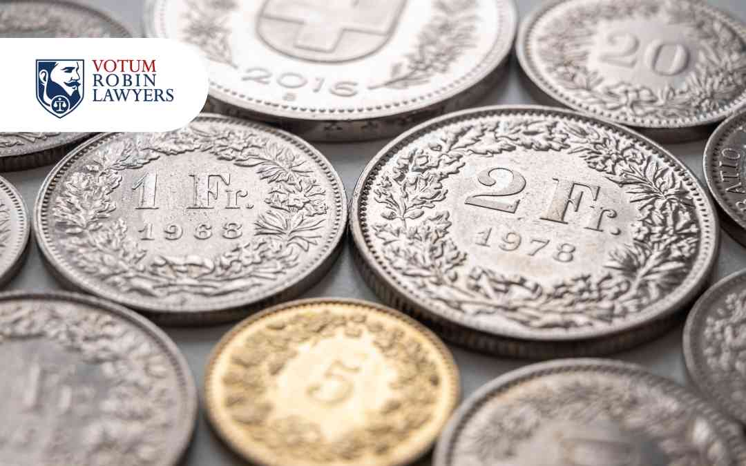 Srebrne monety franka szwajcarskiego rozrzucone na blacie – ilustracja do modelu przeliczenia kredytu na złotowy.