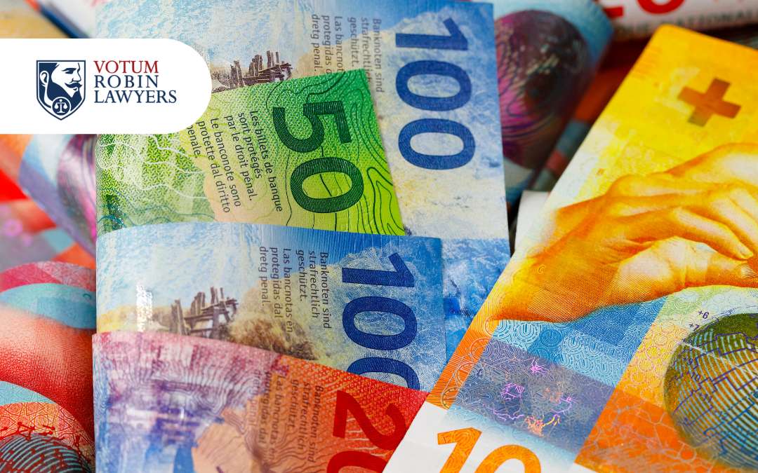 Votum Robin Lawyers logo on a background of colorful banknotes, suggesting legal services related to money or finance.",
