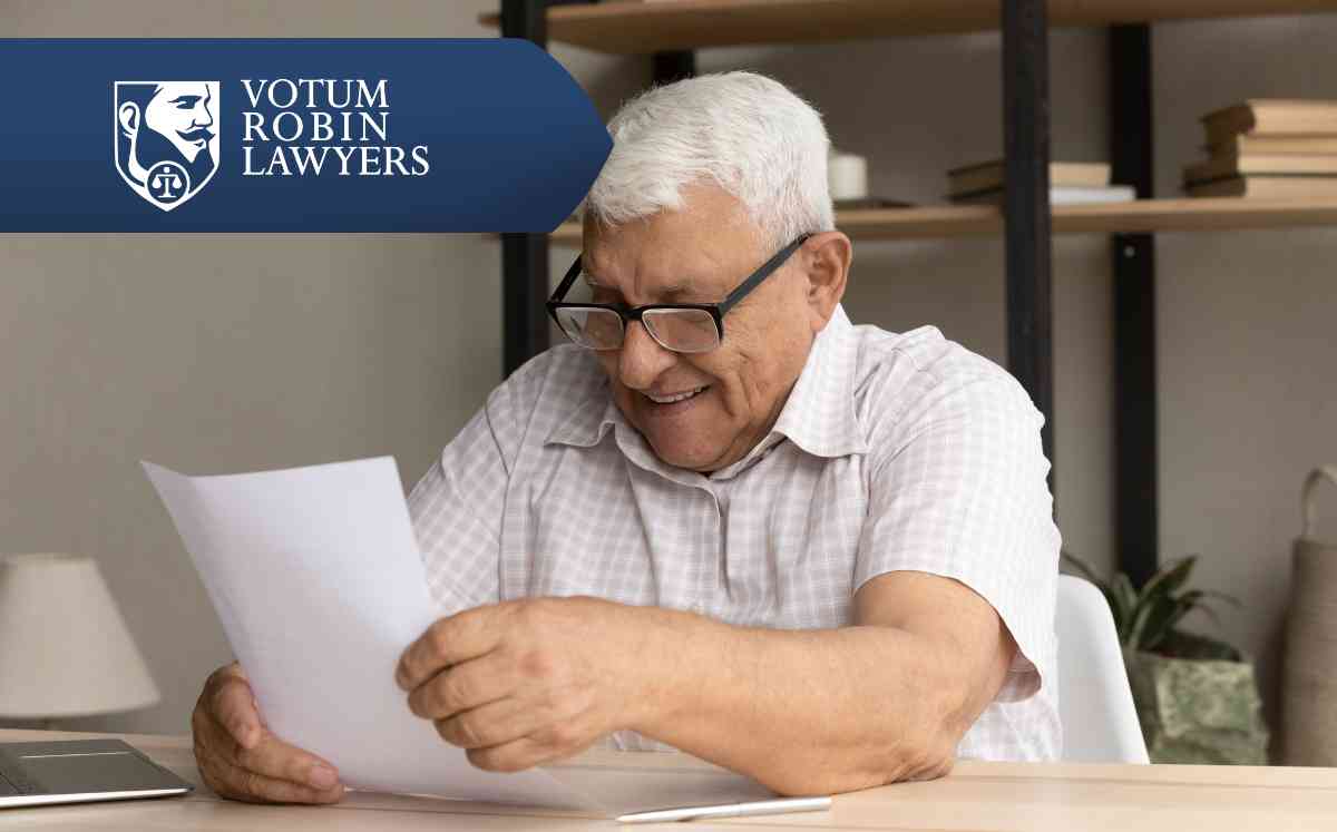 Two lawyers in suits review documents on a desk with a gavel and scales of justice; law firm logo in the corner.
