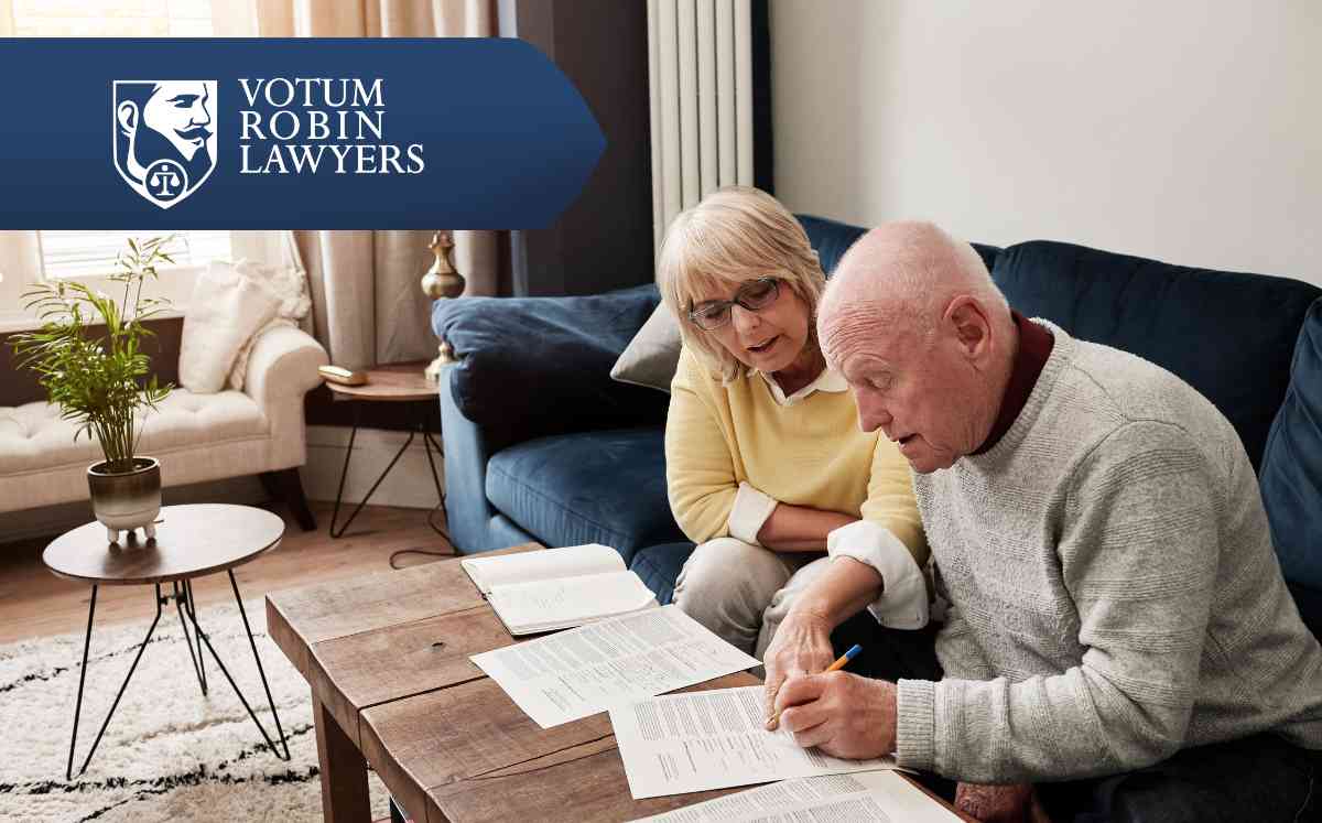 Two lawyers in suits review documents on a desk with a gavel and scales of justice; law firm logo in the corner.