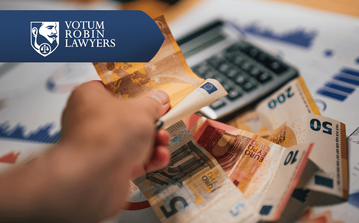 Na obrazku widać euro, kalkulator i dokumenty rozrzucone na biurku